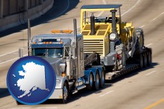 ak map icon and a semi-truck hauling heavy construction equipment